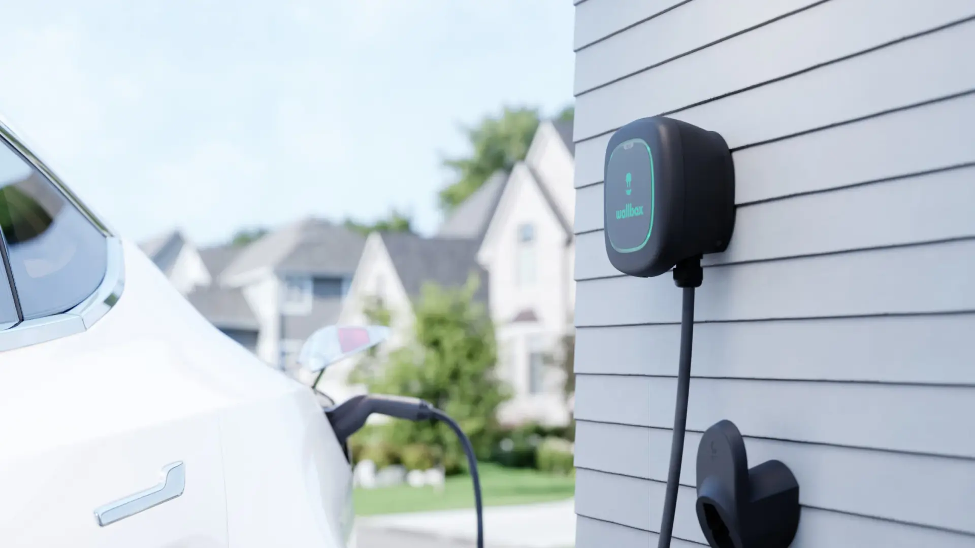 Elektroauto an einer Wallbox vor einem Wohngebäude